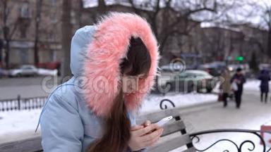 冬天，一个穿着灰色<strong>保暖夹克</strong>的年轻女人在街上用电话。